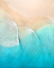 Aerial view of nice gentle waves crashing on an idyllic beach. Illustration of a travel paradise with beautiful blue turquoise water near a holiday destinations. 