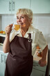 © Viacheslav Yakobchuk - Joyful old woman in apron drinking tea at home
