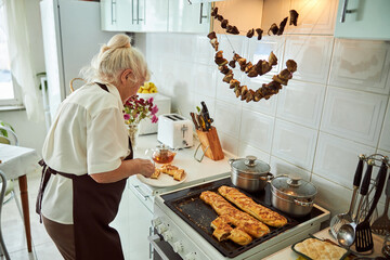 Wall Mural - Lovely old woman placing meat pie on plate