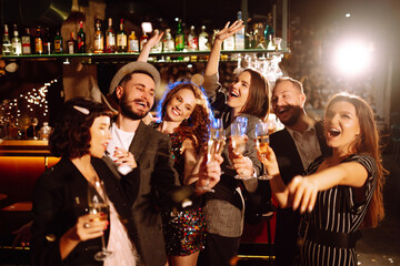 Group of happy people clinking glasses of champagne at party. Young friends celebrating winter holiday together with champagne. Party, celebration, drink, birthday concept.