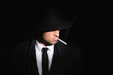 Wall Mural - Old fashioned detective smoking cigarette on dark background