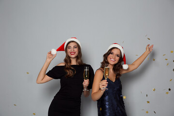 Poster - Happy women in Santa hats with champagne on grey background. Christmas party