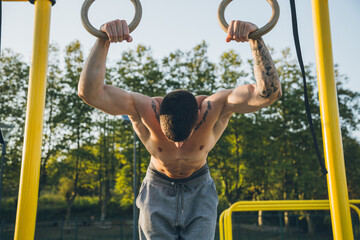 Athletic young man preparing and checking gymnastic rings