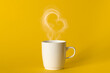 Steaming coffee cup on yellow background. White сoffee cup with steam. Smoke from hot coffee. Front view, copy space