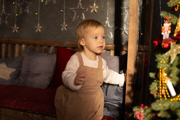 a girl looks at toys on a Christmas tree next to glowing garlands