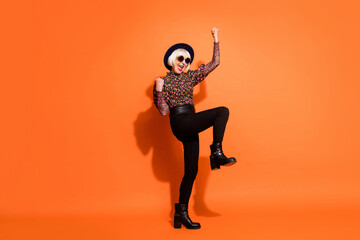 Full size photo of smiling excited crazy hipster old lady raise fists in victory isolated on orange color background