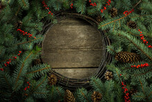 Christmas Rustic Border Design Background. Christmas Wreath On Wooden Background. Christmas Fir Tree Branches On The Table. Round Christmas Evergreen Pine Branches With Red Berries Background.  