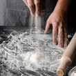 Cook hands kneading dough, sprinkling piece of dough with white wheat flour