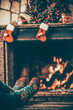 © AlexMaster - Feet in woollen socks by the fireplace. Woman relaxes by warm fire and warming up her feet in woollen socks. Close up on feet. Winter and Christmas holidays concept.