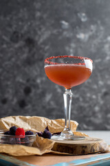 Wall Mural - Cocktail drink in margarita glass with jelly berries on gray background