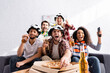 © LIGHTFIELD STUDIOS - excited man shouting, holding beer and taking pizza while watching championship with multicultural friends on blurred foreground