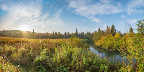Wall Mural - Panorama of the morning sunrise in the river valley, autumn colors on the trees and wet grass from the dew, beautiful blue sky in the clouds.