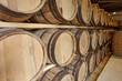 A row of traditional full whisky barrels, set down to mature, in a large warehouse facility