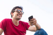 © Jos Temprano/ADDICTIVE STOCK - Attractive young man dressed with red t-shirt smiling with sunglasses and smartphone