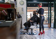 © Jose Carlos Gutierrez/ADDICTIVE STOCK - Side view of stylish female master in black leather pants and red high heels drying hair of bearded male client while working in barbershop