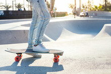 Unrecognizable Stylish Skater In Jeans And Sneakers Standing On Skateboard In Skatepark On Sunny Day In Summer