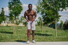 Full Body Of Strong Active African American Male With Naked Muscular Torso Doing Resistance Bend Bicep Curl Exercise During Functional Workout On Street