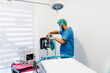 © Victor Gonzalez/ADDICTIVE STOCK - Side view of male vet doctor in uniform and mask preparing anesthesia machine for surgery in bright operating theater in veterinary clinic
