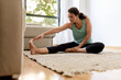 © Sergio Victor Vega/ADDICTIVE STOCK - Peaceful female in sportswear practicing yoga in Seated Forward Bend pose and stretching legs while sitting on carpet in living room
