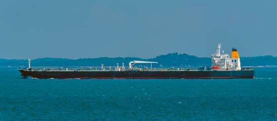 A close up view of a large loaded oil tanker sailing in the Singapore Straits in Asia in summertime