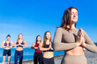 © yurakrasil - unity group of women practic yoga on rhe beach in morning