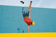 © VISTA by Westend61 - Young man with artificial limb and foot doing handstand against multi colored wall