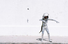 Boy In Astronaut Costume Playing While Standing Against Wall In City