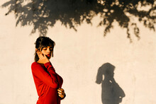 Thoughtful Woman Standing With Eyes Closed By Shadow On Wall During Sunset