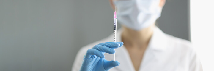 Portrait of doctor in whose hand medical syringe with needle