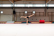 © David Prado/Stocksy - young artistic gymnast woman performing and training somersaults