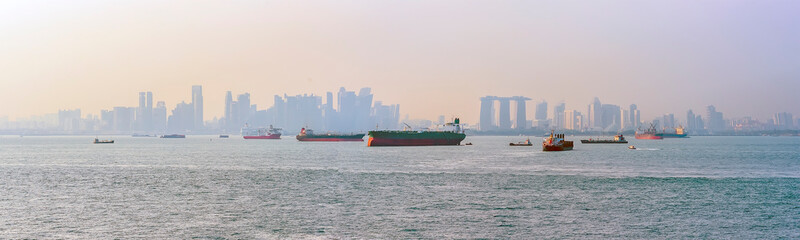 Commercial shipping with Singapore silhouetted in the background at dusk in summertime