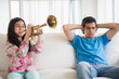 © JGI/Jamie Grill/Blend Images - Hispanic brother covering his ears as sister practices trumpet in living room