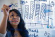 © JGI/Jamie Grill/Blend Images - Pacific Islander businesswoman drawing chart on glass in office