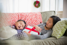 Asian Brother And Sister Napping On Sofa With Christmas Gift