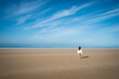 © Alberto Guglielmi/Blend Images - Caucasian woman walking on beach under blue sky