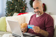 © JGI/Jamie Grill/Blend Images - Mixed race man shopping online with laptop at Christmas