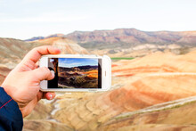 Caucasian Man Taking Cell Phone Photograph Of Desert Landscape, Painted Hills, Oregon, United States