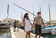 © Alberto Guglielmi/Blend Images - Couple walking on wooden dock in urban harbor