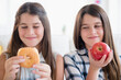 © JGI/Jamie Grill/Blend Images - Caucasian twin sisters eating healthy and unhealthy snacks