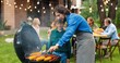 © VAKSMANV - Happy Caucasian father cooking corn and sausages on barbecue together with kid. Family dinner at fresh air at weekend. Man with small son preparing food at back yard. Little helping to dad.