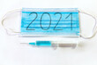 Maseczka chirurgiczna z napisem 2021 i strzykawka. Temat masowych szczepień przeciwko koronawirusowi w 2021 roku