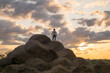 © Aliyev Alexei Sergeevich/Blend Images - Caucasian man standing on rock pile at sunset