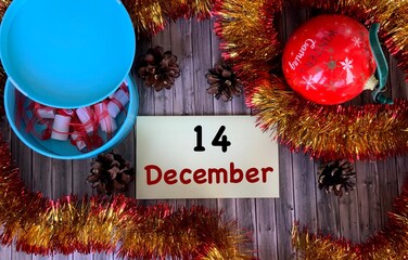 December 14 on a yellow sticker.Christmas balloon, fir cones on a wooden background.The first month of winter.Calendar for December.