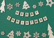 Creative Christmas flat lay composition, inscription Merry Christmas made of wooden blocks with letters and Xmas decorations arranged up and down on green background. Greeting card, holiday wishes.