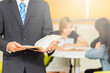 © shine - Young male teacher holding books in library.