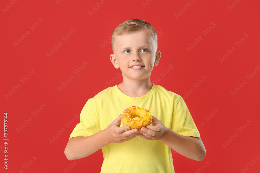 Funny little boy with donuts on color background