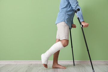 Young man with broken leg near color wall