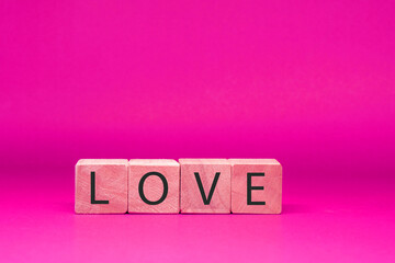 Wall Mural - Love word , Text on wooden block object on pink background and copy space - Pink Valentine celebrate concept                                