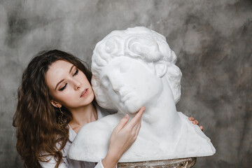 beautiful curly girl sitting hugging with a plaster statue