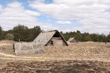 Wall Mural - traditional old rustic building with a roof covered with straw on early spring day, Ukraine. tourist place